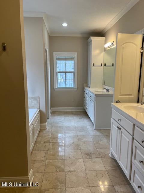 bathroom featuring ornamental molding, two vanities, baseboards, and a sink