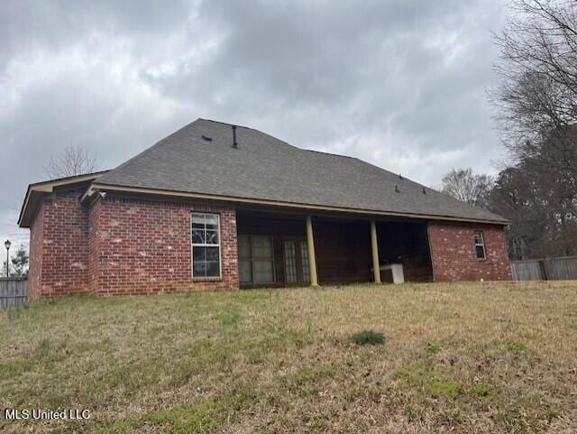 rear view of house with a yard and brick siding