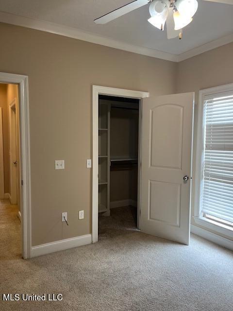 unfurnished bedroom with light carpet, a closet, crown molding, and baseboards