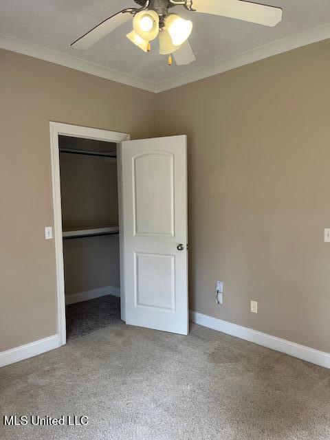 unfurnished bedroom featuring baseboards, ornamental molding, light carpet, a closet, and a ceiling fan