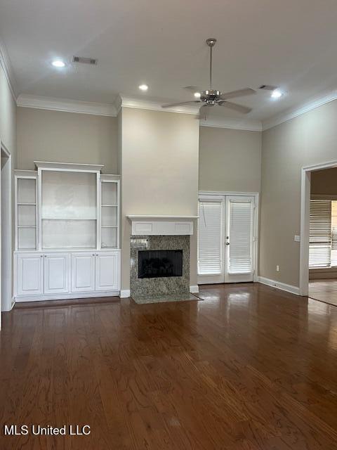 unfurnished living room with a high end fireplace, wood finished floors, a ceiling fan, and ornamental molding