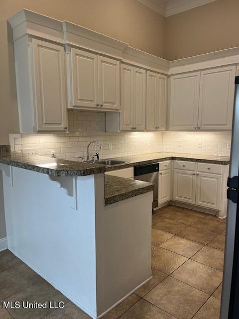 kitchen with a peninsula, ornamental molding, a sink, white cabinets, and appliances with stainless steel finishes