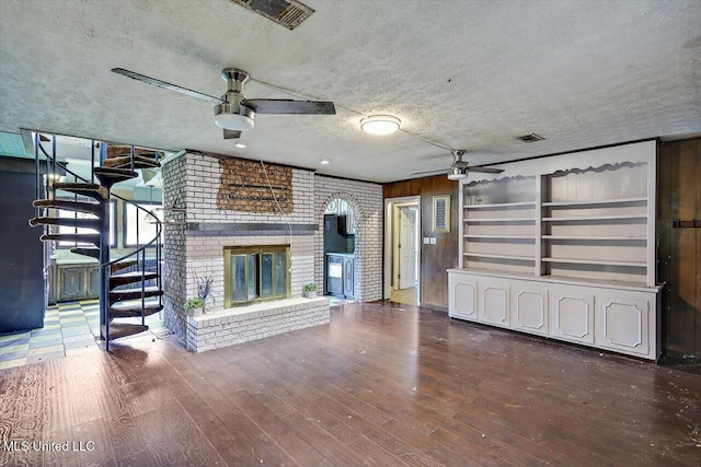 unfurnished living room with dark hardwood / wood-style flooring, ceiling fan, a fireplace, and a textured ceiling