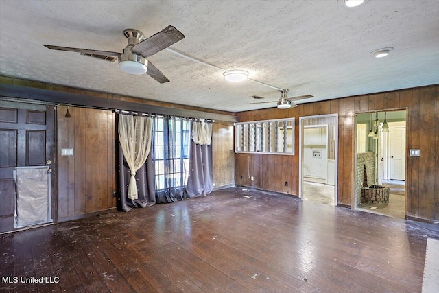 unfurnished living room featuring hardwood / wood-style flooring, a textured ceiling, ceiling fan, and wood walls