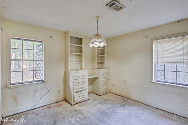 unfurnished dining area featuring a textured ceiling and a healthy amount of sunlight