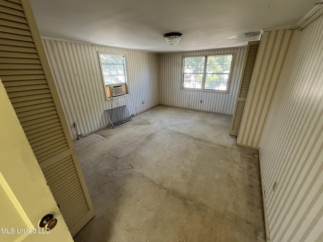 carpeted empty room featuring cooling unit, plenty of natural light, and ornamental molding