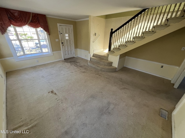 entrance foyer featuring crown molding and carpet floors