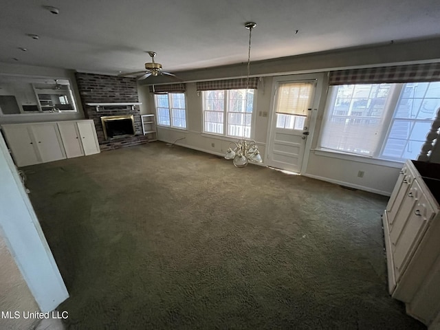 unfurnished living room with a brick fireplace, dark carpet, and ceiling fan