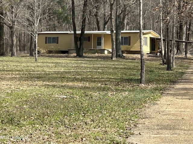 manufactured / mobile home with a view of trees and a front lawn