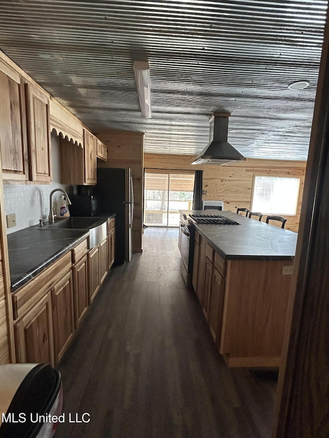 kitchen with dark wood-style flooring, a sink, black range with gas cooktop, dark countertops, and exhaust hood