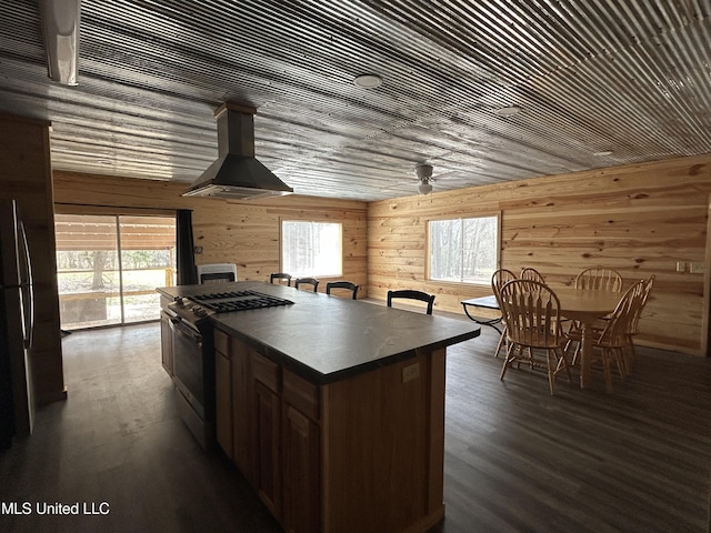 kitchen with dark wood-type flooring, range with gas stovetop, dark countertops, a kitchen island, and range hood