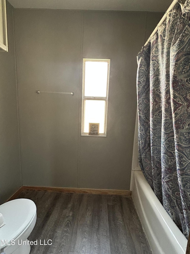 bathroom featuring shower / bath combination with curtain, toilet, wood finished floors, and baseboards