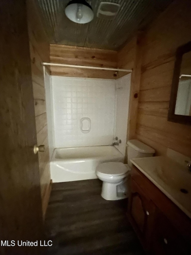 full bath with toilet, wood finished floors, wood walls, bathing tub / shower combination, and vanity