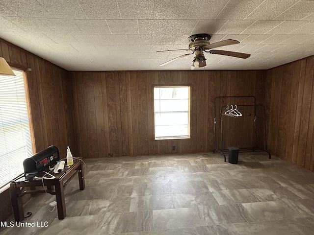 unfurnished room with wood walls and ceiling fan