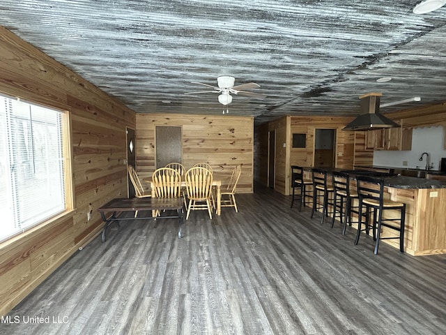 dining room featuring ceiling fan, wood finished floors, and wood walls