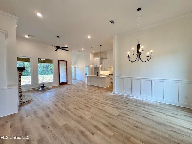 unfurnished living room with ceiling fan with notable chandelier, sink, a brick fireplace, ornamental molding, and light hardwood / wood-style floors