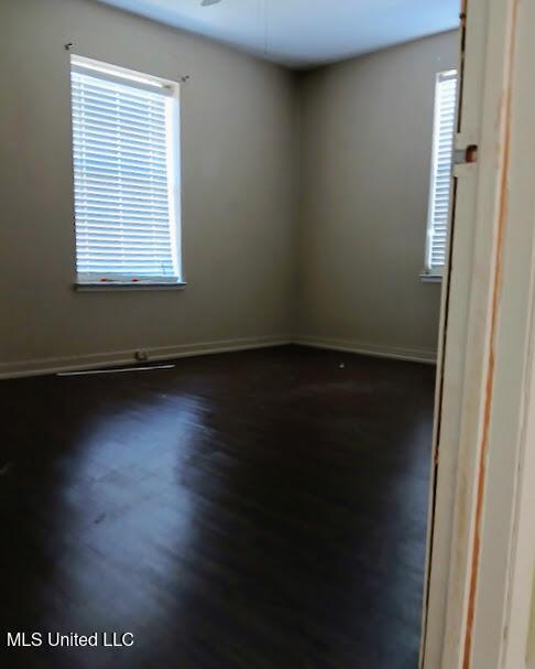 unfurnished room featuring dark wood-type flooring and ceiling fan