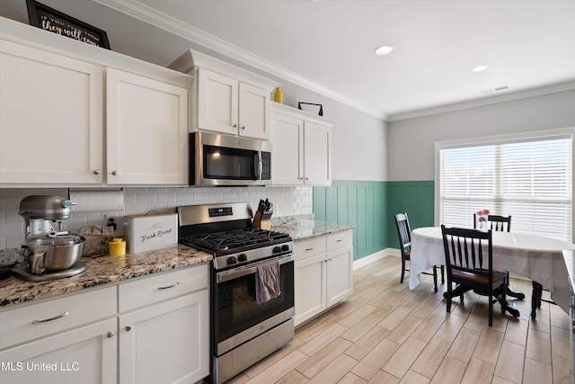 kitchen featuring visible vents, white cabinets, appliances with stainless steel finishes, and crown molding