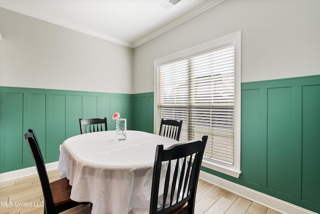 dining area with visible vents, wainscoting, light wood-style flooring, and crown molding