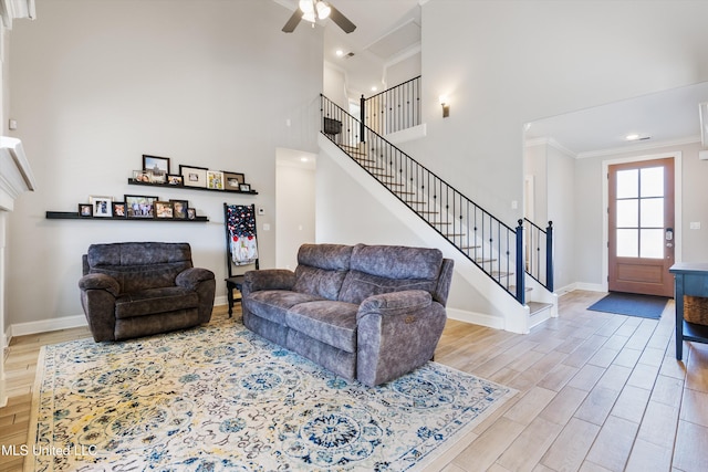 living area featuring baseboards, wood finished floors, stairs, and ornamental molding