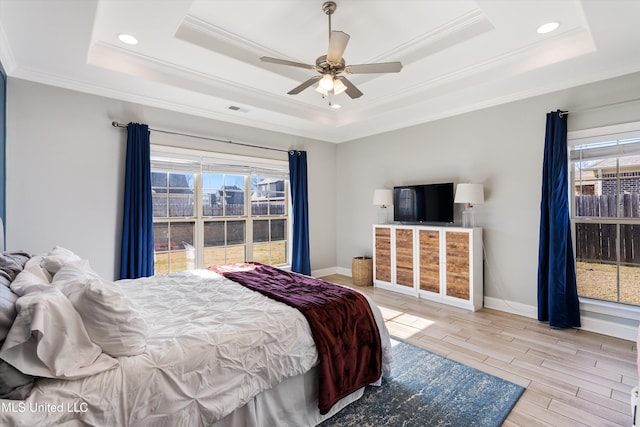 bedroom with multiple windows, a raised ceiling, and wood finished floors