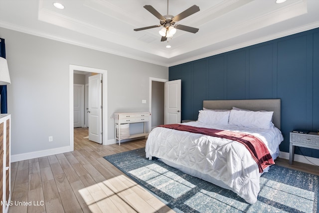 bedroom with baseboards, a raised ceiling, wood finished floors, and crown molding