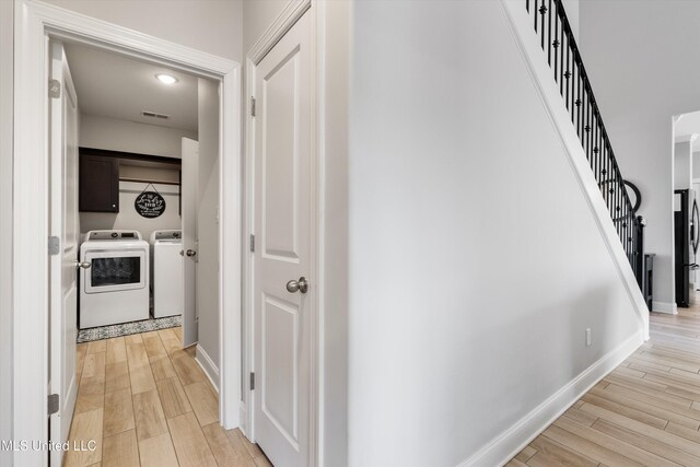 hallway with light wood-type flooring, visible vents, stairway, and washer and clothes dryer