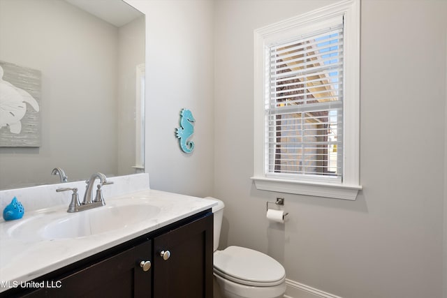 half bathroom featuring baseboards, toilet, and vanity