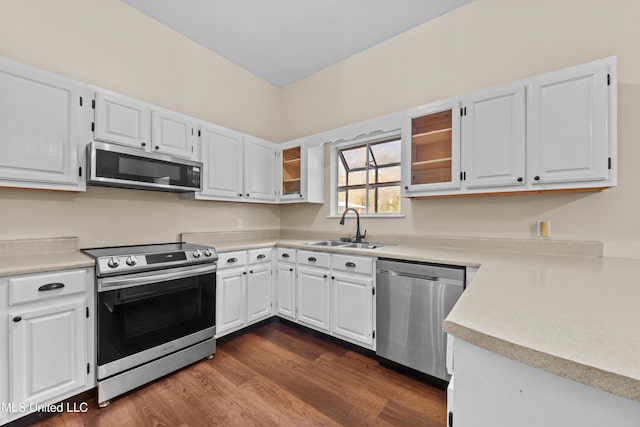 kitchen with appliances with stainless steel finishes, dark hardwood / wood-style flooring, white cabinetry, and sink