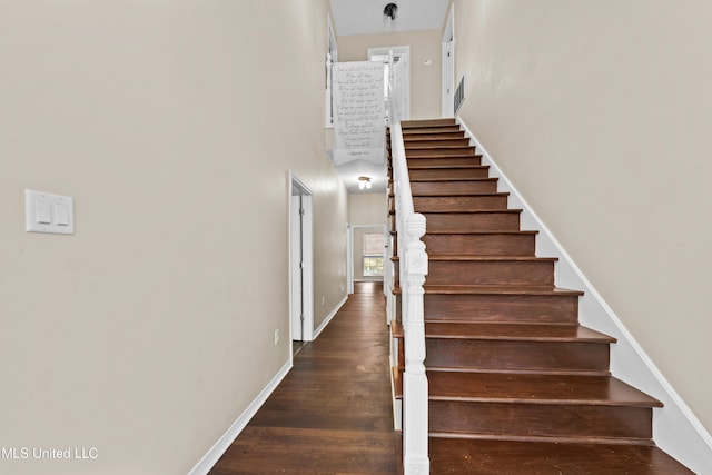 staircase with hardwood / wood-style flooring and a high ceiling