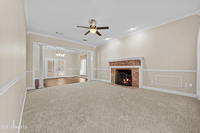 unfurnished living room featuring carpet, french doors, a fireplace, ceiling fan, and crown molding