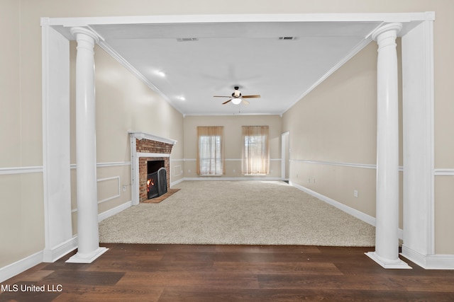 unfurnished living room featuring decorative columns, ceiling fan, dark hardwood / wood-style floors, a fireplace, and crown molding