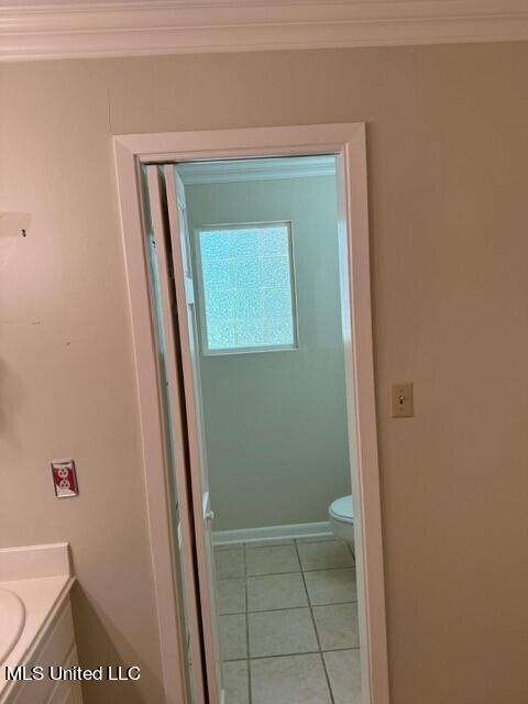 bathroom with toilet, vanity, crown molding, tile patterned flooring, and baseboards