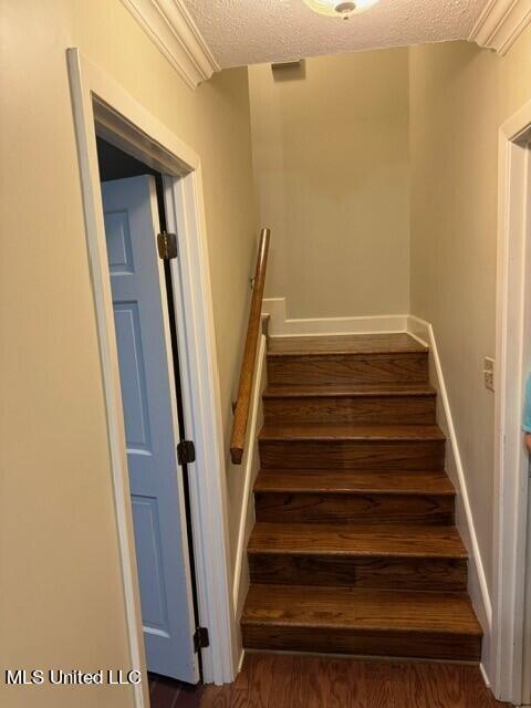 staircase featuring a textured ceiling and wood finished floors