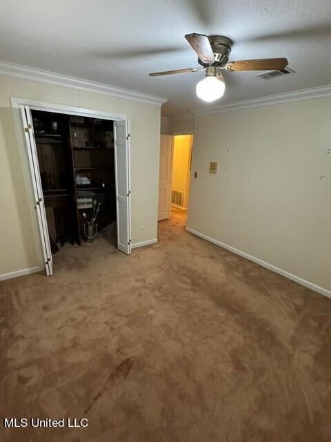 unfurnished bedroom with carpet flooring, visible vents, baseboards, and ornamental molding