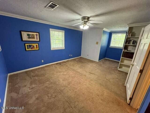 unfurnished bedroom with a textured ceiling, ornamental molding, visible vents, and carpet