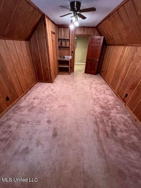bonus room featuring vaulted ceiling, light carpet, wood walls, and ceiling fan