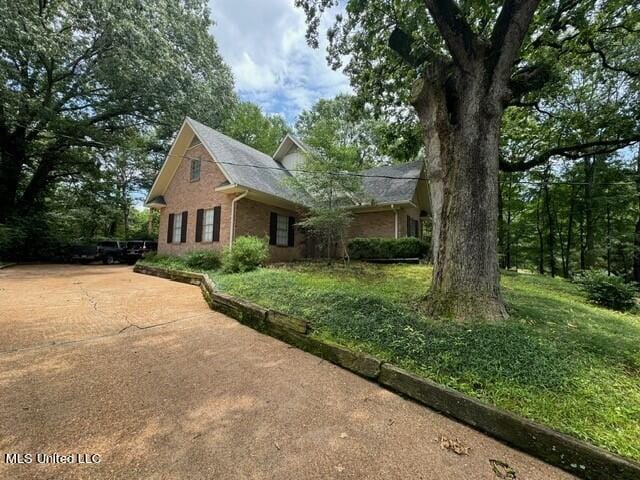 view of side of property featuring brick siding and driveway