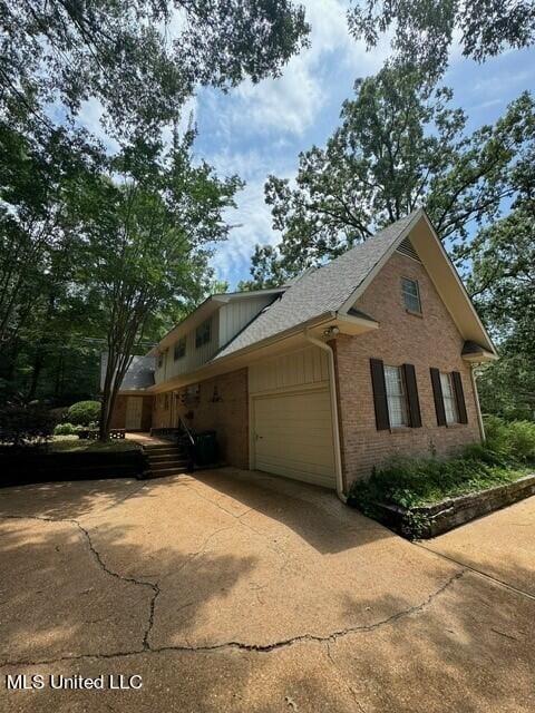 view of home's exterior featuring concrete driveway, brick siding, and a garage