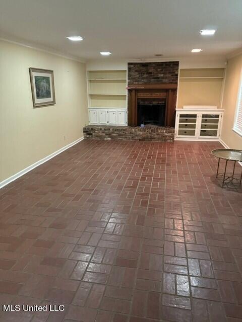 unfurnished living room with a brick fireplace, brick floor, baseboards, and recessed lighting