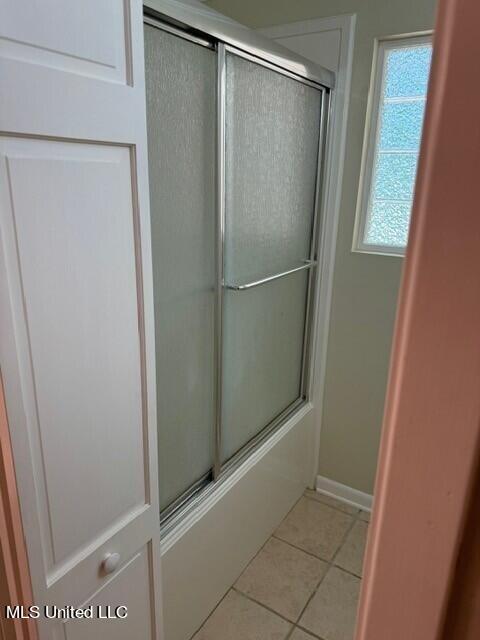 bathroom with bath / shower combo with glass door, baseboards, and tile patterned floors