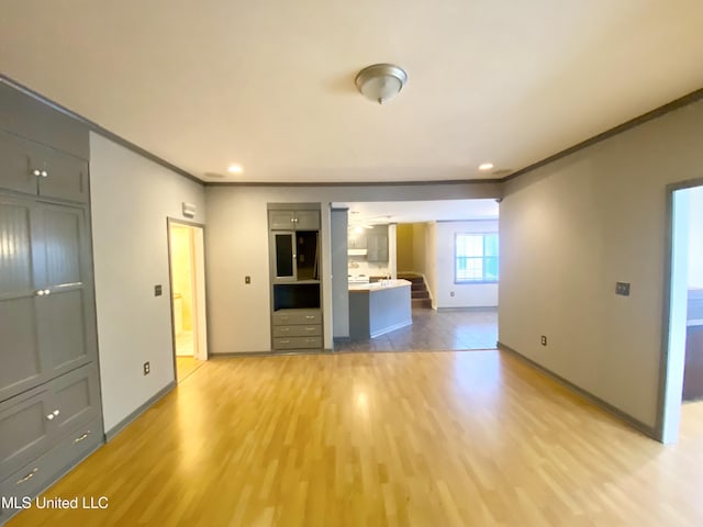 unfurnished living room featuring ornamental molding and light hardwood / wood-style flooring