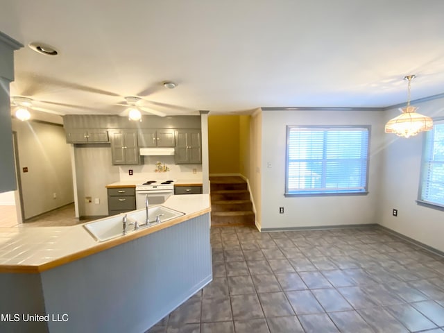 kitchen featuring white stove, gray cabinets, hanging light fixtures, and a healthy amount of sunlight