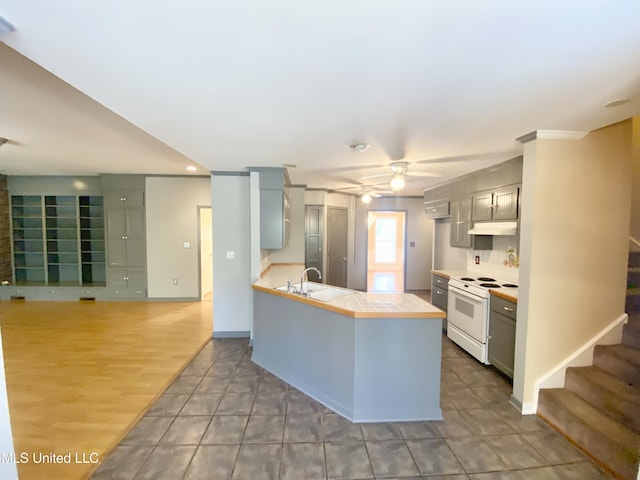 kitchen featuring ceiling fan, sink, white electric range, kitchen peninsula, and wood-type flooring