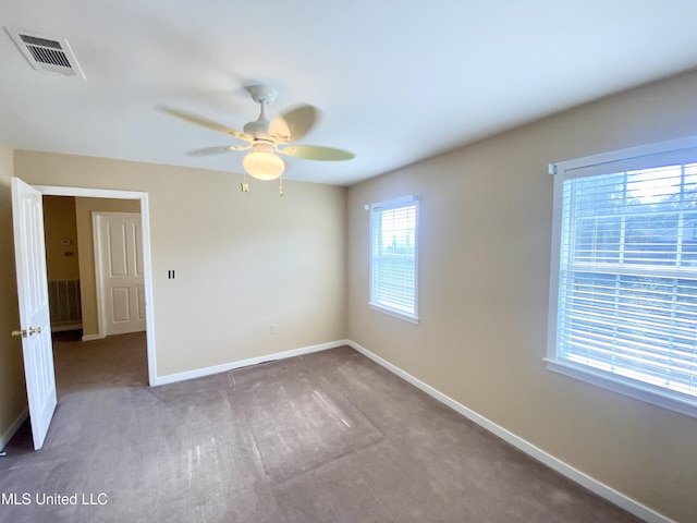 carpeted empty room featuring ceiling fan and plenty of natural light