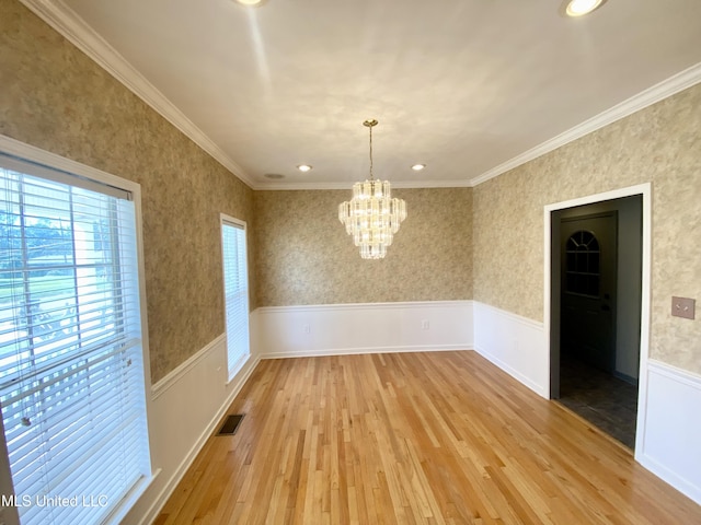 unfurnished dining area with light wood-type flooring, ornamental molding, and an inviting chandelier