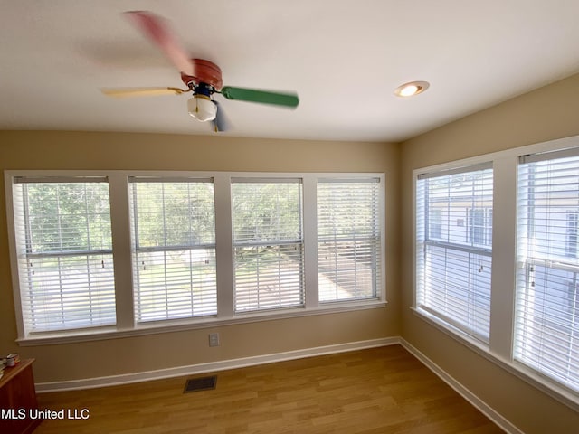 unfurnished sunroom with ceiling fan and a healthy amount of sunlight