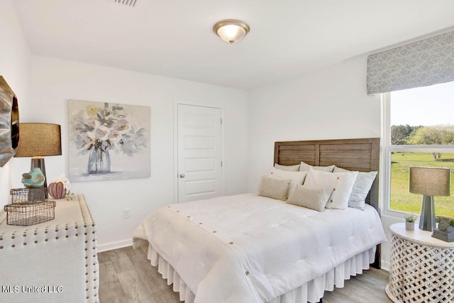 bedroom with multiple windows and light wood-type flooring