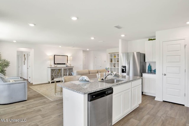 kitchen featuring stainless steel appliances, an island with sink, and white cabinets