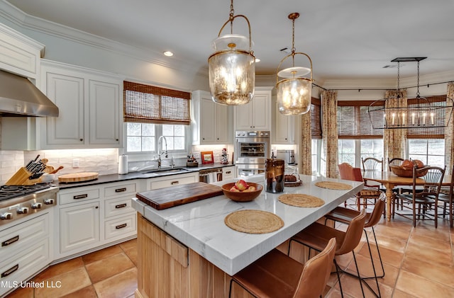 kitchen featuring a center island, sink, white cabinetry, and pendant lighting